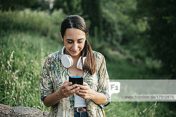 Smiling woman messaging from smart phone at park