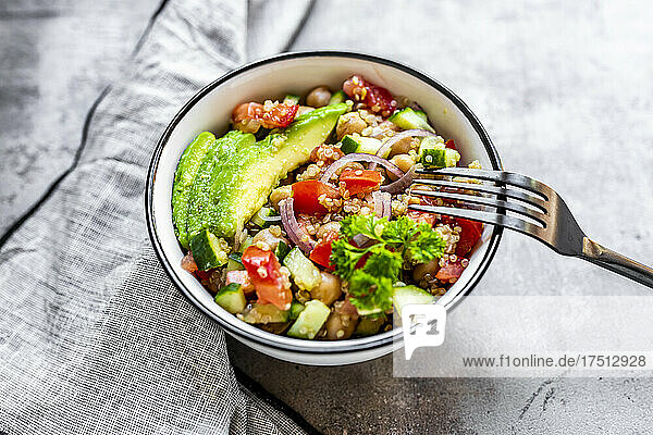 Bowl of vegetarian quinoa salad with chick-peas  avocado  cucumber  tomato  onion and parsley