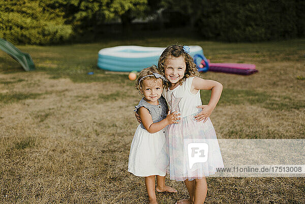 Portrait of two cute sisters hugging on a meadow
