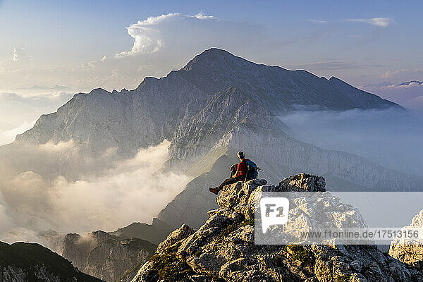Hiker sitting on mountain peak at Bergamasque Alps  Italy