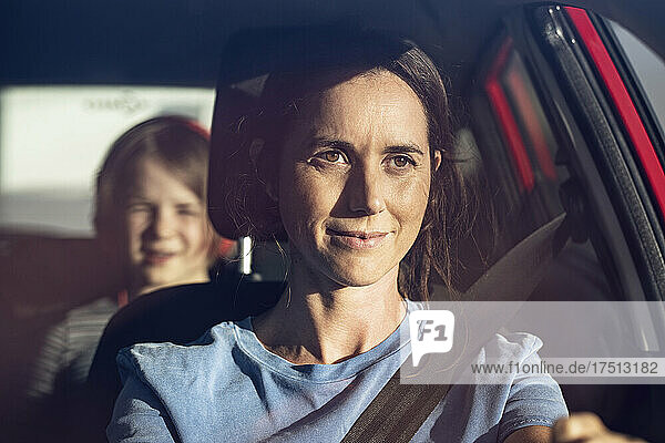 Young woman driving car with seat belt  daughter in backseat