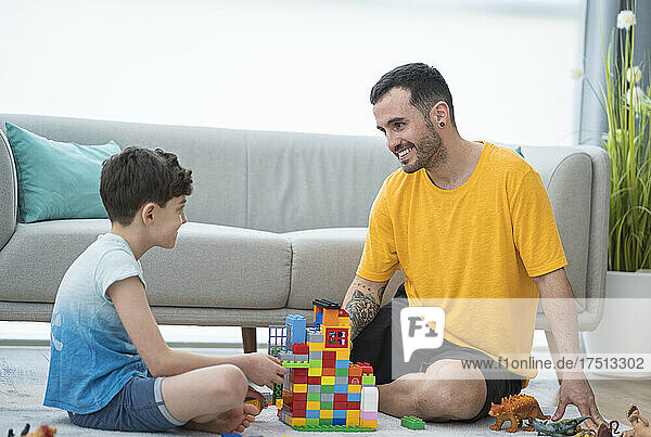 Smiling father playing with son in living room