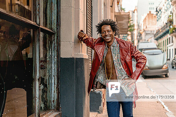 Happy retro man wearing leather jacket while standing on sidewalk in city