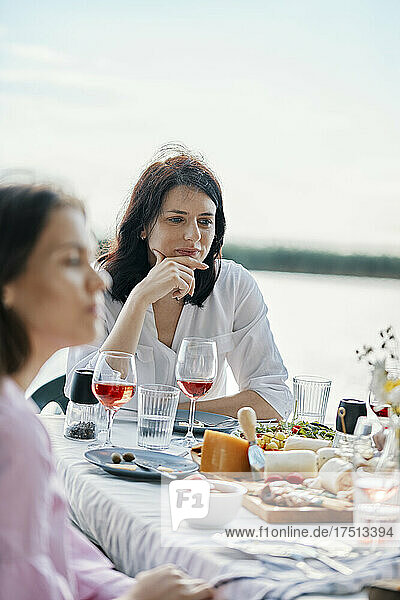 Junge Frau beim Abendessen mit Freunden am Seeufer