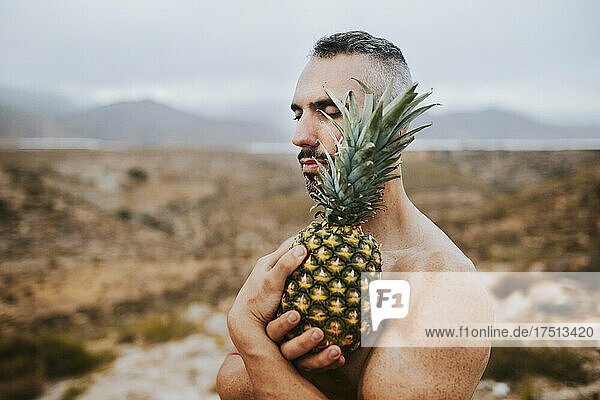 Mann hält Ananas im Feld bei Sonnenuntergang