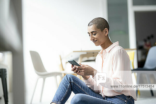 Woman sitting on the floor in a loft using smartphone
