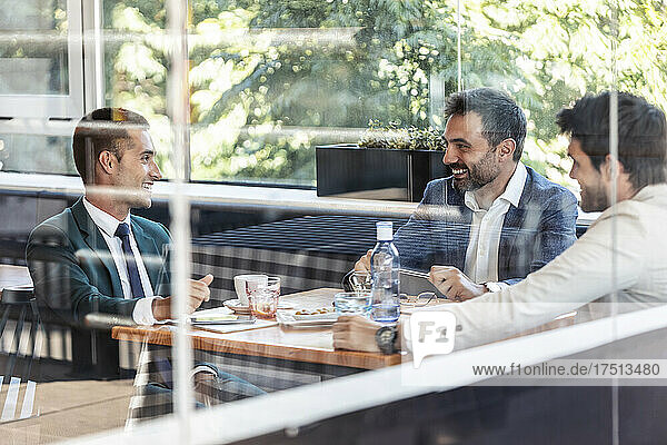 Smiling businessmen discussing at table during meeting at cafe