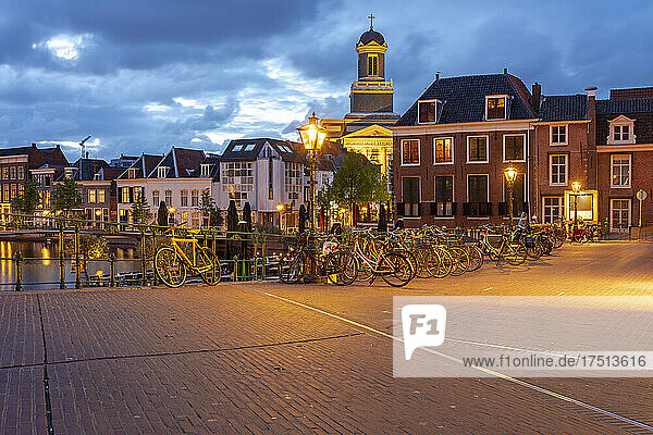 Netherlands  South Holland  Leiden  Bicycles parked along illuminated old town street at dusk