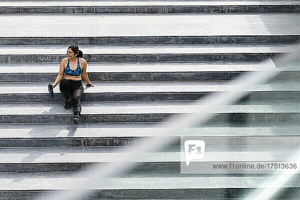 Young athletic woman sitting on stairs during break