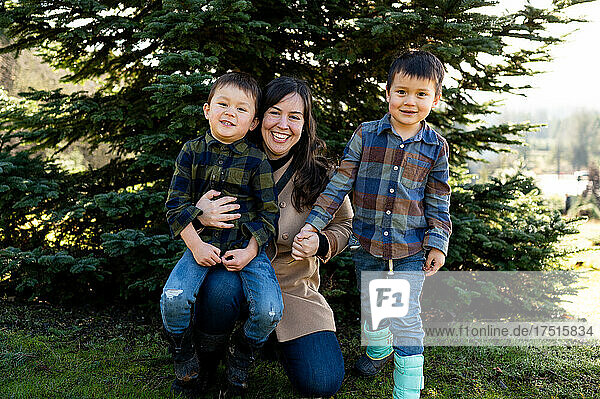 Happy mom with boys in front of Christmas Tree on Farm