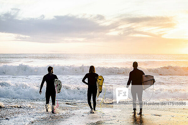 surfing boys entering the water at sunrise  background waves