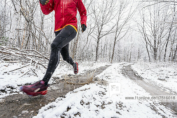 A woman in a red Jacket running in mud in winter.