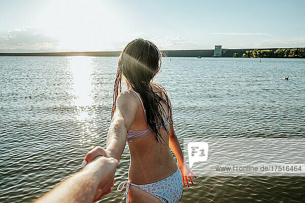 Close up of teen girl leading someone into a lake