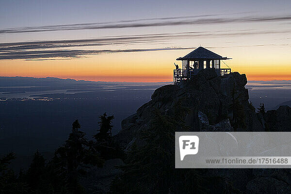 Silhouette of a person on a fire lookout at sunset