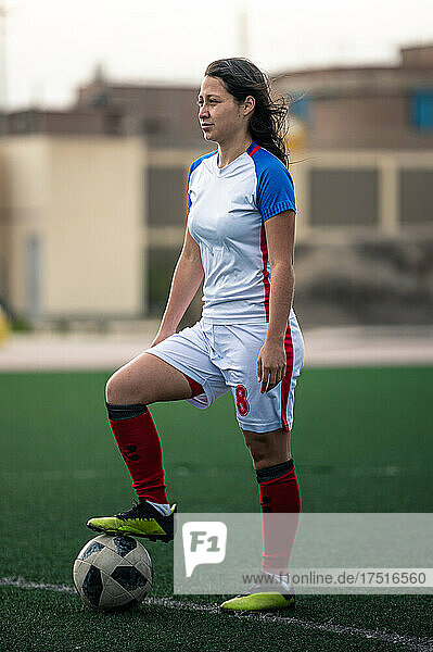 portrait of young female soccer player steps on the ball on the field