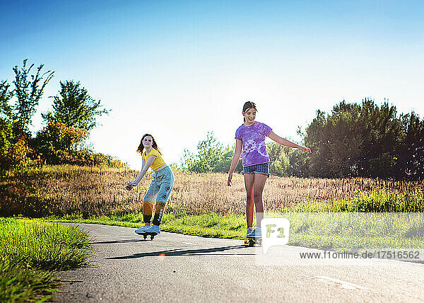 Two happy tween girls ripsticking and skateboarding.