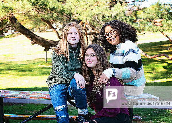 Three happy tween girls outdoors at a park.