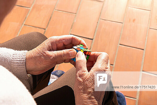 Senior woman solving a rubik's cube to improve memory on sunny day