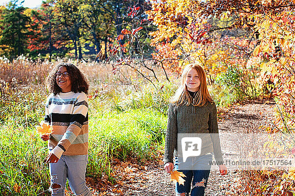Two pretty tween girls laughing together outdoors in fall colors.