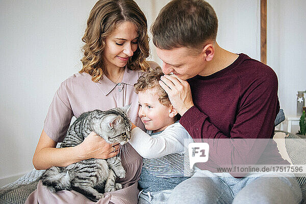 Father and mother hold their son and cat on hands. Tender moment
