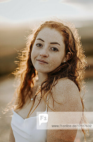 Portrait of smiling red haired girl in white top with setting sun