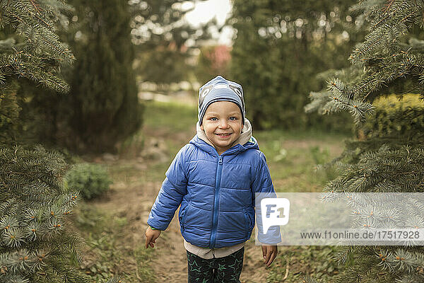 Small boy in blue clothes in garden smiling