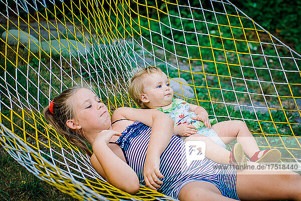 Teenager girls and child having fun in the garden on a hammock