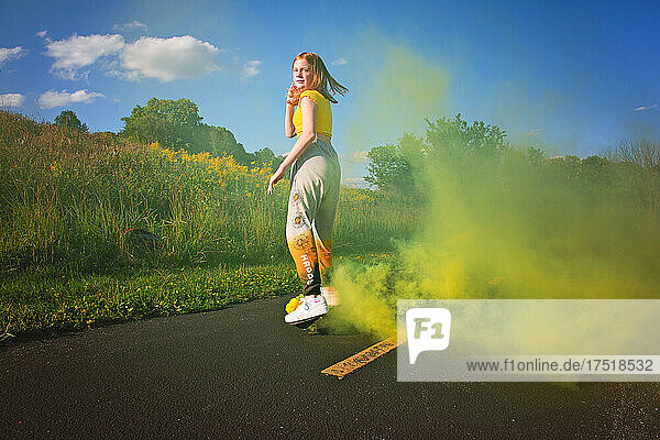 Happy tween girl skateboarding with smokebomb.