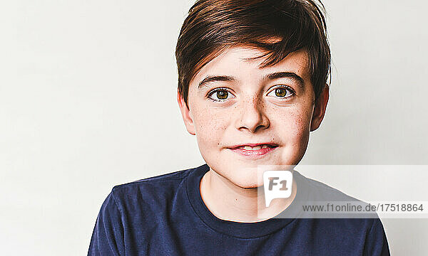 Close up portrait of cute young boy with brown hair and freckles.