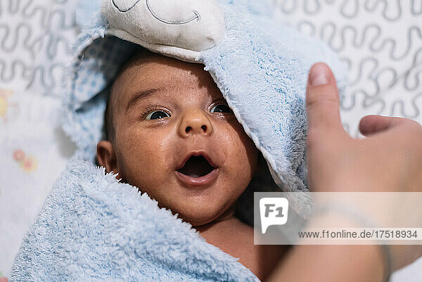 Newborn baby wrapped in a bath towel. Screaming happily.