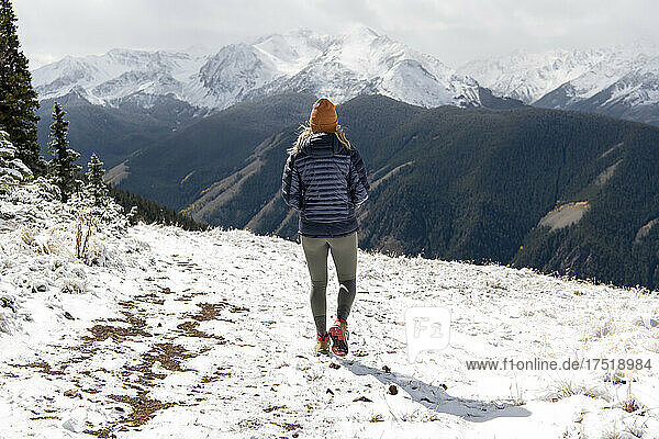 Rear view of woman walking on snow covered mountain during winter