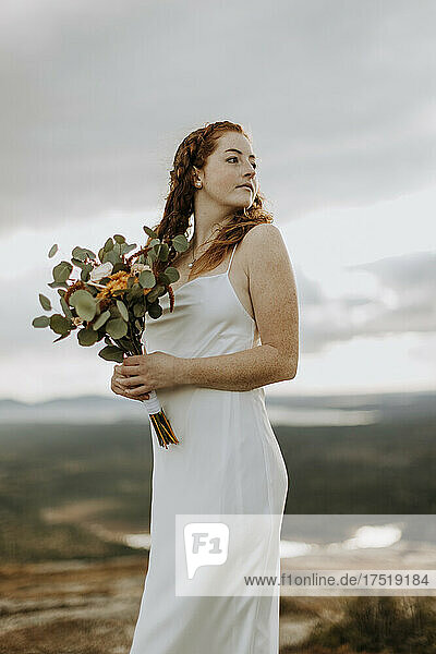 portrait of red hair bride in wedding dress and flowers outside