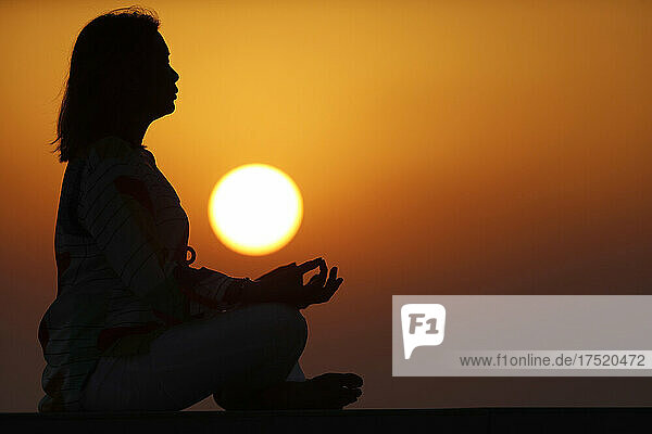 Woman practising yoga pose and meditation at sunset as concept for silence and relaxation  United Arab Emirates  Middle East
