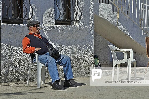 Man with cap and waistcoat sitting on chair smoking cigar  Villaricos  Andalucia  Spain  Europe