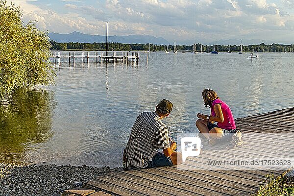 Mann und Frau sitzen abends am Steg  Kleines Seehaus  Pischetsried  St. Heinrich  Starnberger See  Oberbayern