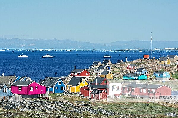 Verschiedenfarbige Holzäuser vor der Bucht mit Eisbergen  im Hintergrund die Diskoinsel  Illimanaq  Diskobucht  Avannaata Kommunia  Arktis  Grönland  Dänemark  Nordamerika