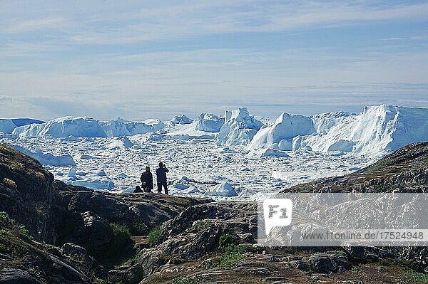 Menschen sitzen vor Fjord  der mit Eis und Eisbergen überdeckt ist  Eisfjord  Sermermuit  Sommer  Arktis  Ilulissat  Grönland  Dänemark  Nordamerika