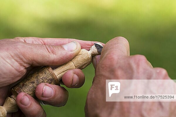 Man carving a small wooden figure  close-up with hands  wood and carving knife. Värmland  Sweden  Europe