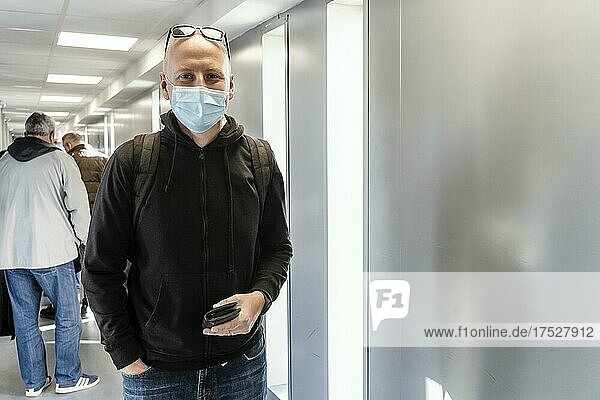 Ein Tourist mit Schutzmaske und Rucksack wartet am Flughafen auf das Boarding