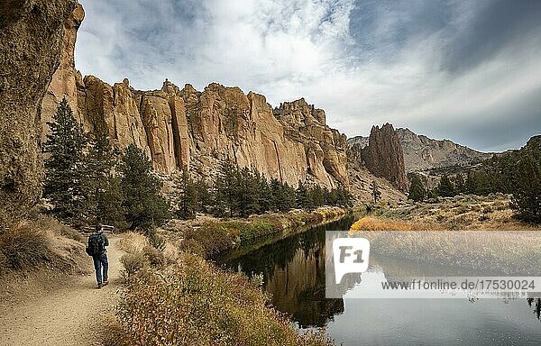 Hiker on hiking trail  rock walls reflected in the course of the Crooked River  canyon with rock formations  The Red Wall  Smith Rock State Park  Oregon  USA  North America