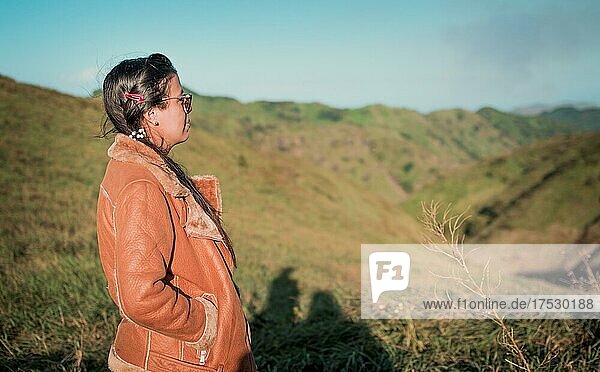 Mädchen auf dem Feld mit Blick auf den Horizont  Frau in Jacke mit Brille auf einem Hügel