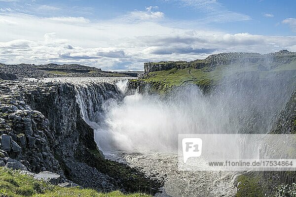 Woman standing in front of gorge  canyon with falling water masses  Dettifoss waterfall in summer  North Iceland  Iceland  Europe
