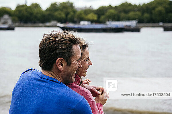 Happy man embracing woman at riverbank
