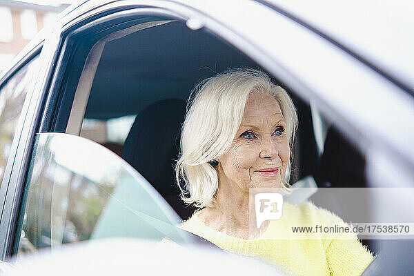 Smiling senior woman with white hair driving car