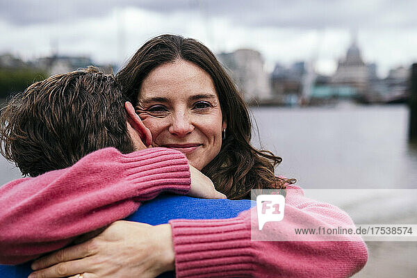 Lächelnde Frau umarmt Mann am Flussufer