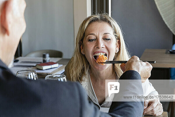 Mann füttert Frau beim Mittagessen im Restaurant mit Stäbchen mit Sushi
