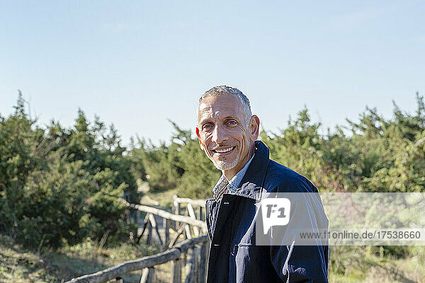 Smiling man in jacket on wooden bridge