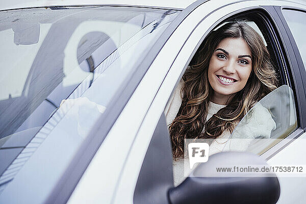 Young smiling woman looking through car window
