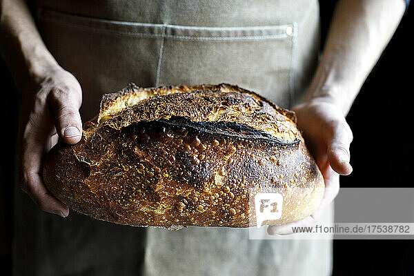 Baker holding loaf of fresh baked bread