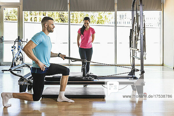 Fitness instructor guiding athlete to exercise with gym equipment